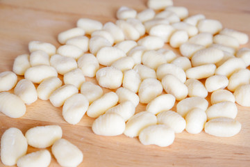 Traditional gnocchi, handmade italian pasta, with tomatoes on wooden table, natural light