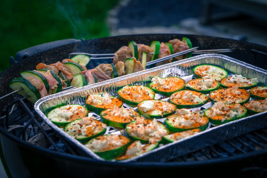 Zucchinischeiben mit Feta &uuml;berbacken und Schweinelendchen Spie&szlig;e auf einem Kohlegrill