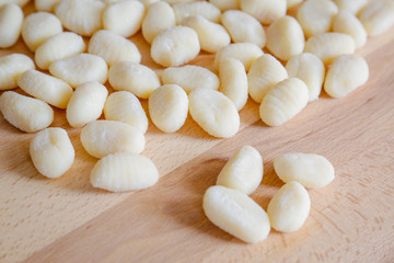 Traditional gnocchi, handmade italian pasta, with tomatoes on wooden table, natural light