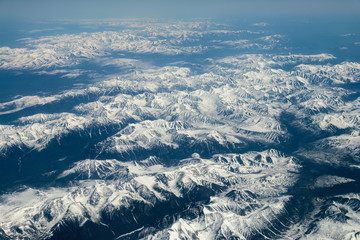 View from airplane on Earth surface - snow-capped mountains.