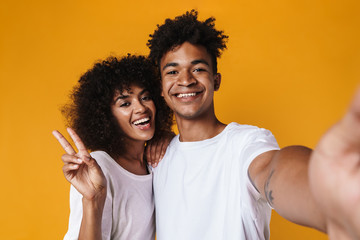 Image of african american couple gesturing peace sign while taking selfie