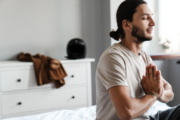 Young man meditating in bedroom