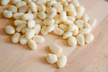 Traditional gnocchi, handmade italian pasta, with tomatoes on wooden table, natural light