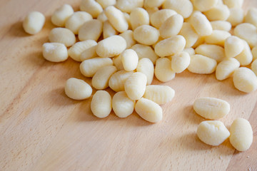 Traditional gnocchi, handmade italian pasta, with tomatoes on wooden table, natural light