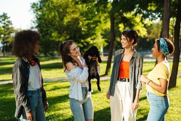 Happy young girls spending time in park, holding puppy dog