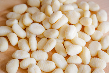 Traditional gnocchi, handmade italian pasta, with tomatoes on wooden table, natural light