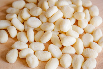 Traditional gnocchi, handmade italian pasta, with tomatoes on wooden table, natural light