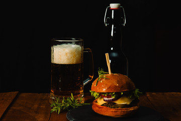  Delicious hamburger with mug of beer on wooden table