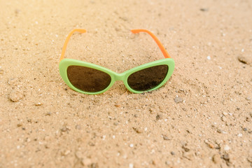 Fototapeta na wymiar Close up green sunglasses on the sand.