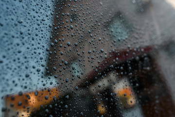 Reflection of a house in a blue glass with raindrops.