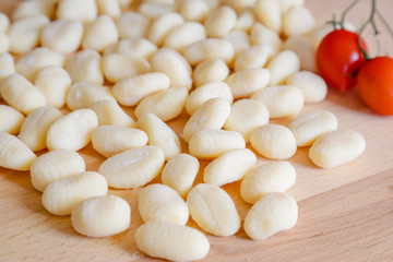 Traditional gnocchi, handmade italian pasta, with tomatoes on wooden table, natural light