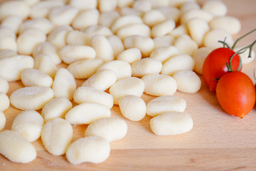 Traditional gnocchi, handmade italian pasta, with tomatoes on wooden table, natural light