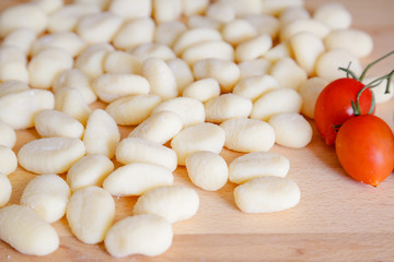 Traditional gnocchi, handmade italian pasta, with tomatoes on wooden table, natural light