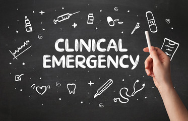 Hand drawing CLINICAL EMERGENCY inscription with white chalk on blackboard, medical concept