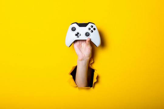 Female hand holds a joystick on a bright yellow background
