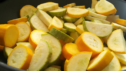 Green zucchini and zucchini in a black wok. Vegan food.