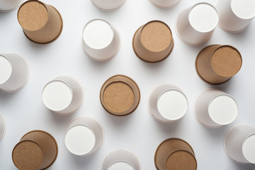 White and brown paper cups flipped upside down on a light background. Top view, flat lay
