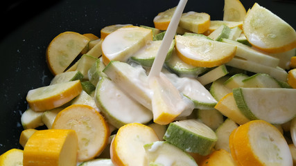 Green zucchini and zucchini in a black wok. Vegan food.