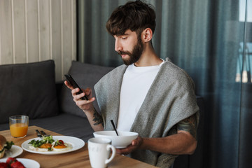 Attractive young bearded man using mobile phone