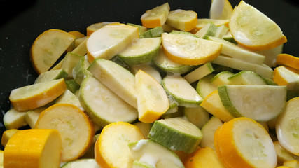 Green zucchini and zucchini in a black wok. Vegan food.