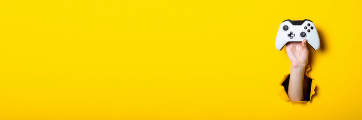 Man's hand holding a stick on a bright yellow background. Banner. © Alex