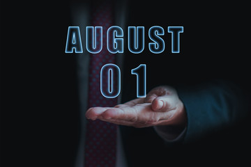 august 1st. Day 1 of month,  announcement of date of  business meeting or event. businessman holds the name of the month and day on his hand.. summer month, day of the year concept