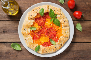 Delicious homemade rustic open pie (galette) with colorful tomatoes and basil leaves .