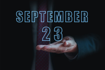 september 23rd. Day 23 of month, announcement of date of business meeting or event. businessman holds the name of the month and day on his hand. autumn month, day of the year concept