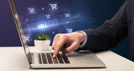 Businessman working on laptop with SELL inscription, online shopping concept