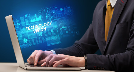 Businessman working on laptop with TECHNOLOGY VISION inscription, cyber technology concept