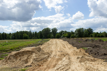 Initial stage of construction of a new wide road in the countryside. Yellow sand in the meadow...