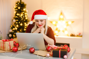 Woman using laptop near Christmas tree, online christmas