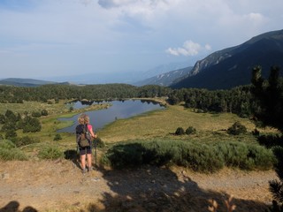 Fototapeta na wymiar Randonnée en Pyrénées orientales lac de Nohèdes en Occitanie et jeune femme randonneuse en montagne qui marche avec bâtons