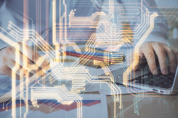 Technology theme hologram with man working on computer on background. High tech concept. Multi exposure.