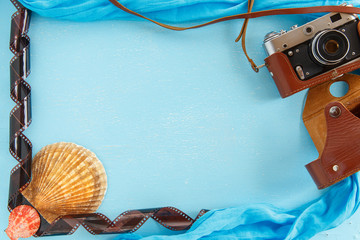 Blank paper photo frame with starfish, shells and items on wooden table.