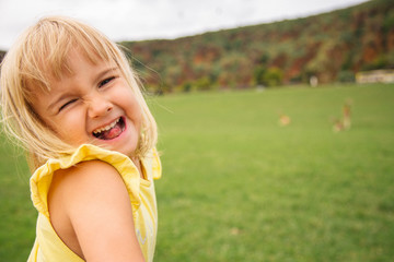 Little blondie girl laughing at camera with sticking out the tongue