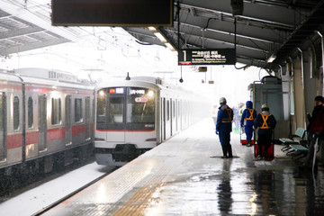 雪が降る東京都内の駅に到着する電車