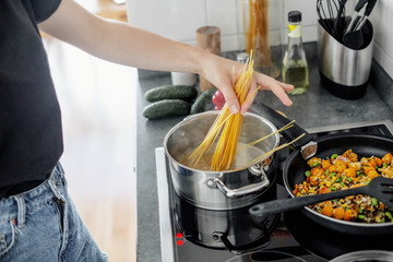 Young woman cooking pasta at home kitchen