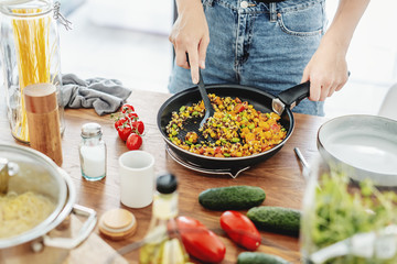 Young woman cooking vegetables at home kitchen
