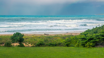 Fototapeta na wymiar Ocean wave rolling towards sandy beach with green trees of Taiwan island