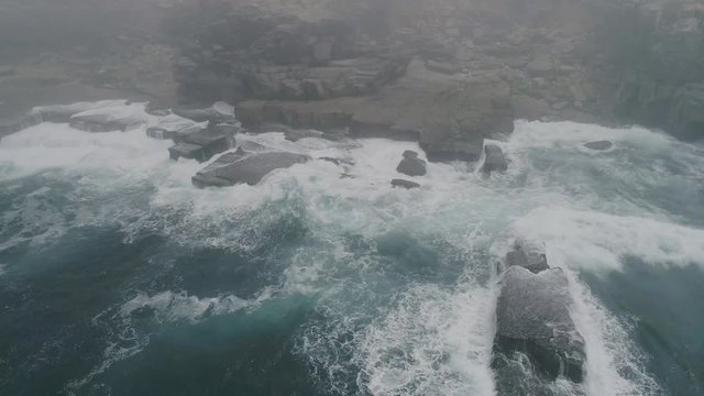 Acantilados con niebla y mar enfurecido desde punto de vista a&eacute;reo