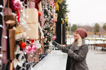 woman on street looking at shop windows decorated for Christmas