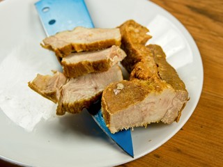 Sliced cured pork belly with blue knife on the white plate