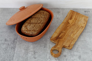 Whole bread loaf in clay bread box with Italian word 