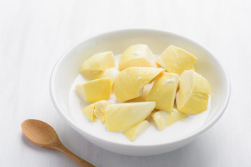 Thai dessert, sliced durian fruit with coconut milk in a bowl on white table background