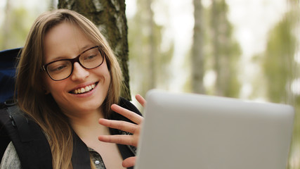Young woman tourist resting in the park and having a video call on tablet. High quality photo