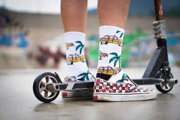 Close-up of a young boy on a scooter. He is going to jump on the ramp and do tricks. 