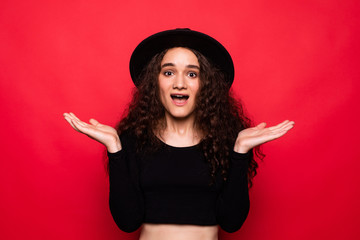 Excited shocked young woman standing isolated over red background.