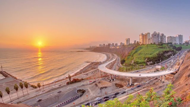 Aerial sunset view of Lima's Coastline in the neighborhood of Miraflores timelapse with orange light, Lima, Peru. Road traffic with junction and beach with ocean from Husares De Junin waterfront