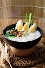 Asian food, Rice soup with boiled egg, grilled mushroom and spinach in a bowl on woven rattan sheet